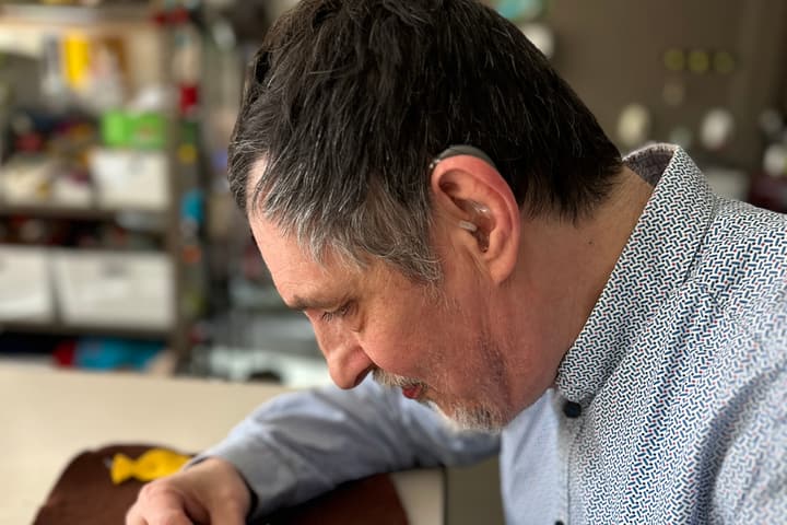 Bewoner met hoortoestel werkt geconcentreerd aan een creatieve opdracht.